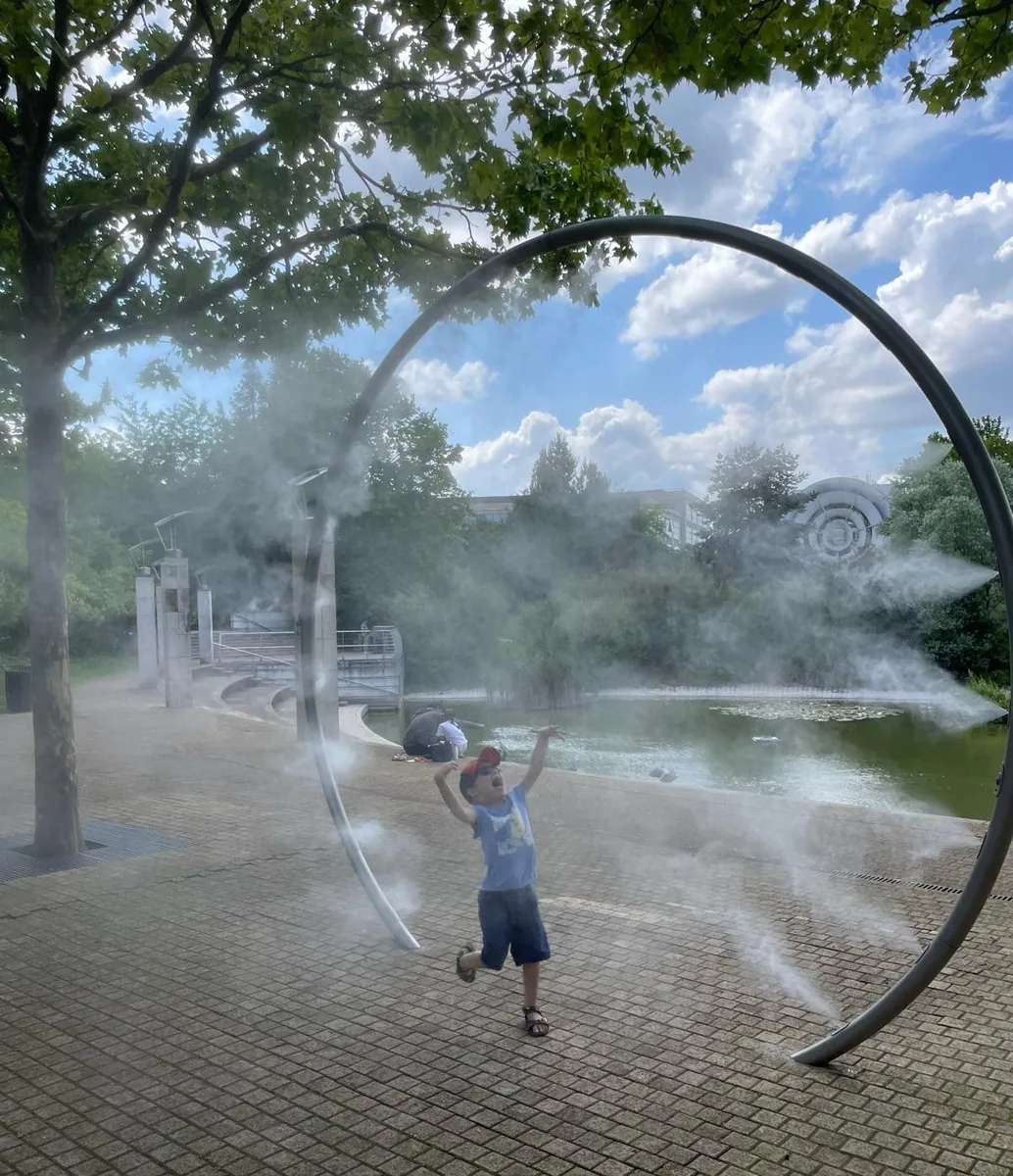 Enfant traversant une arche de brume sur une place