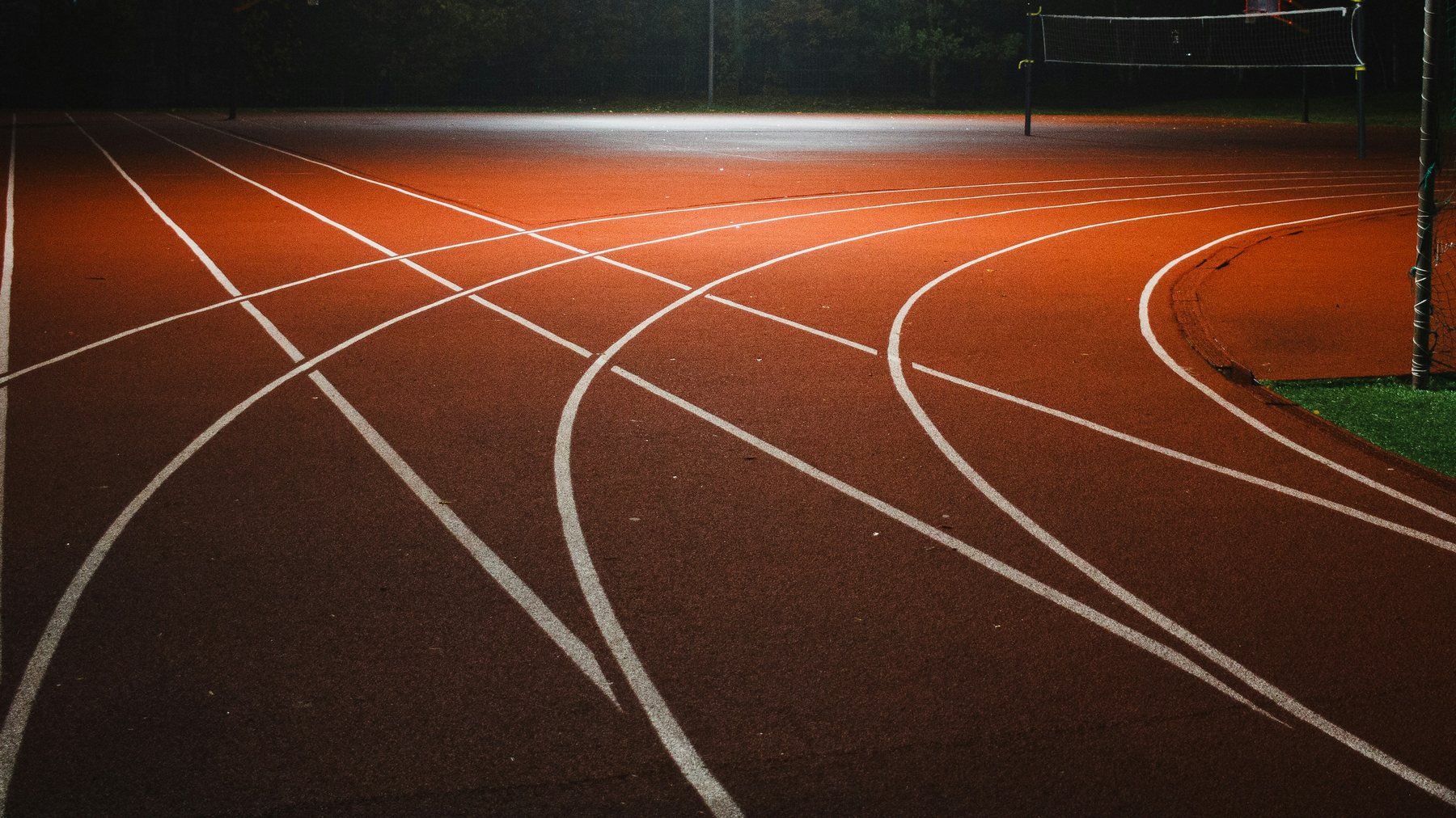 Piste d'athlétisme éclairée de nuit, couloirs et virage, sans projecteur dans le cadre